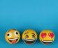Three emoji balls expressing joy, laughter, and love on a bright blue backdrop.