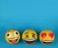 Three emoji balls expressing joy, laughter, and love on a bright blue backdrop.